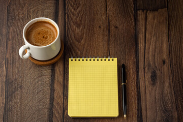 Aroma cup of coffee, blank notepad and pen on wooden table