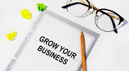 On a sheet from the diary text GROW YOUR BUSINESS, next to a pencil, glasses.
