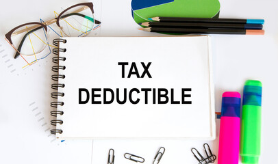 In the notebook, the text OF TAX DEDUCTIBLE, next to the highlighters for the text, next to the glasses, the diagrams.