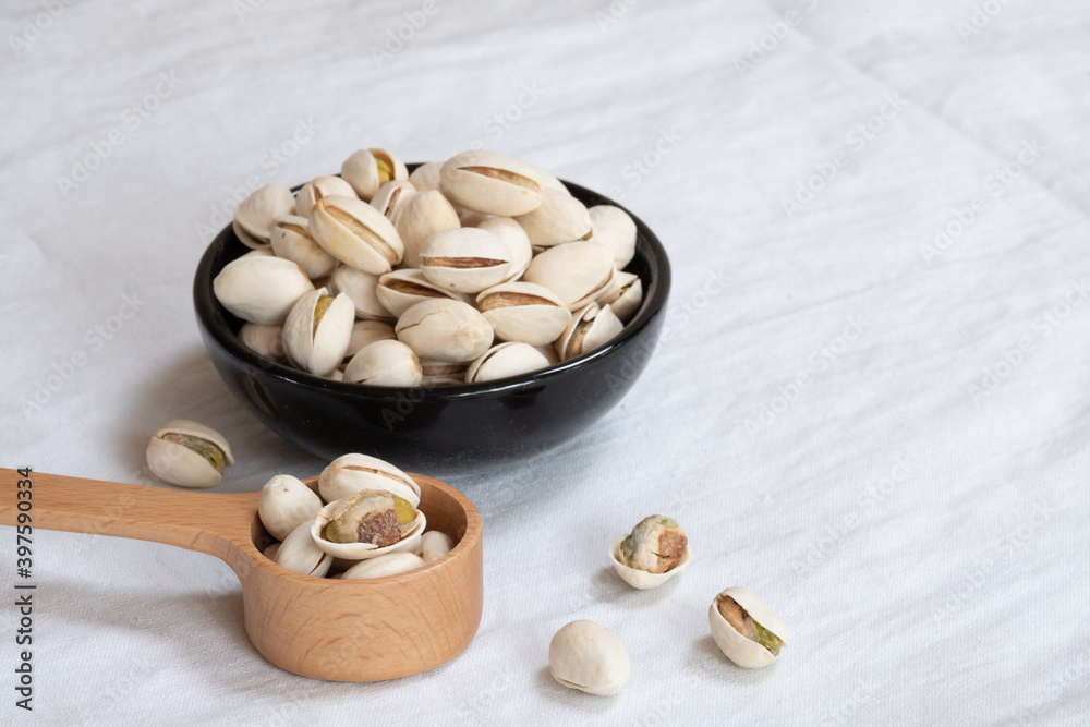 Wall mural Pistachio nut in wooden bowl on white table background - Wall murals