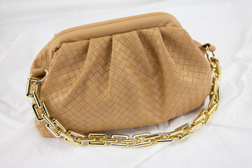 Women handbag with black sunglasses on a white background. Leather bag on a gathered fabric. Side...