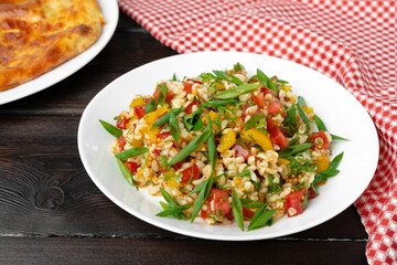Georgian Tabbouleh salad with bulgur and vegetables on black wooden table