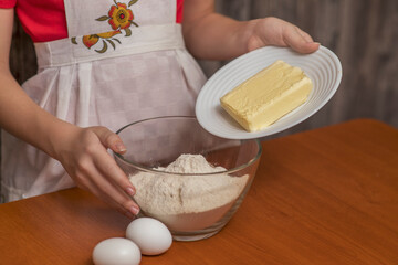 The girl adds butter to the cookie dough. Homemade baking.