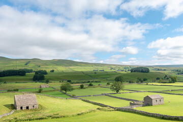 Fototapeta na wymiar Cotterdale, Yorkshire Dales National Park, York, England - A view of an old stone barn, sheep and the rolling landscape of the Yorkshire Dales.