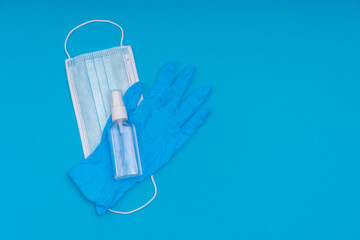 Fototapeta na wymiar Popular medical antiviral mask, syringe with virus vaccine and antiseptic sanitizer on a blue background. A set of essential items during a viral pandemic