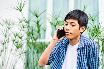 Young asian handsome pre teen boy smiling calling with smartphone at home.Portrait of asian teenager man with smart phone talking with mentor.Technology 5g communication.Stay at home.Stay safe.covid19