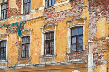 Fototapeta na wymiar Fragment of the facade of an old mansion with peeling plaster