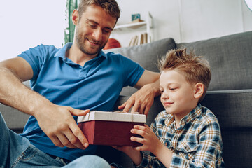 Father gives a present in box to his little son