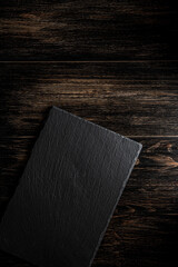 Dark gray slate plate on vintage brown wooden back. Table setting.