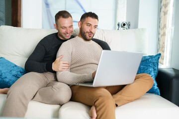 Gay couple consulting their travel plans together with a laptop.