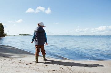A little boy playing near the lake.