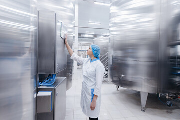 Worker female operator in uniform uses process control panel food factory production line and steel...
