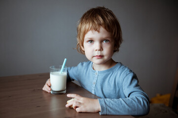 Cute preschooler boy drinking milk from a straw.