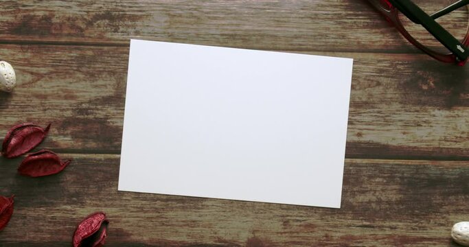 Feminine desktop mockup with blank white paper card, vintage eyeglass and red colour Pot Pourri on brown shabby table background. For web banner. Stylish flat lay, top view