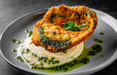 schnitzel with mashed potatoes and pesto sauce on plate
