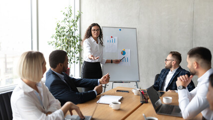 Businesswoman Giving Speech Pointing At Blackboard During Meeting In Office