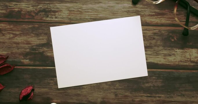 Feminine desktop mockup with blank white paper card, vintage eyeglass and red colour Pot Pourri on brown shabby table background. For web banner. Stylish flat lay, top view, slow dynamic zoom