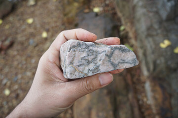 Hand holding a piece of feldspar rock on nature background. 