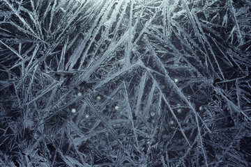 White freeze, ice crystal texture on blue background with bokeh.