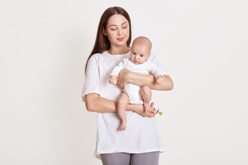 Closeup portrait of beautiful European woman holding on hands her little daughter on white background. Family, love, lifestyle, motherhood and tender moments.