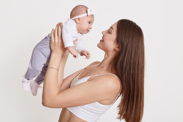 Cute baby in arms of mother isolated over white background, woman holding child girl, attractive...