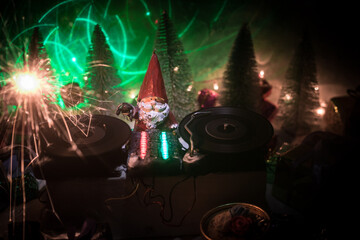 Dj mixer with headphones on dark nightclub background with Christmas tree New Year Eve. Close up view of New Year elements on a Dj table. Holiday party concept. Empty space