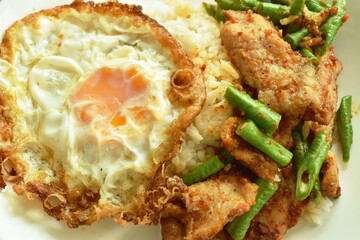 spicy stir fried fermenting soft pork and slice yard long bean curryeat couple plain rice  topping crispy egg on plate