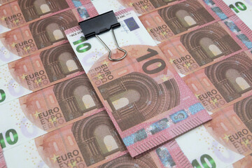 A bundle of banknotes sealed with a stationery clip lies on 10 Euro banknotes
