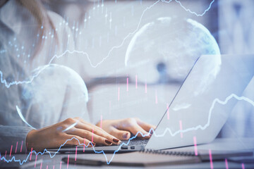 Double exposure of woman hands working on computer and forex graph hologram drawing. Financial analysis concept.