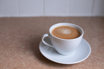 A white cup of hot coffee is prepared on the table - this is a wonderful invigorating drink for breakfast. aromatic fresh coffee in the morning.