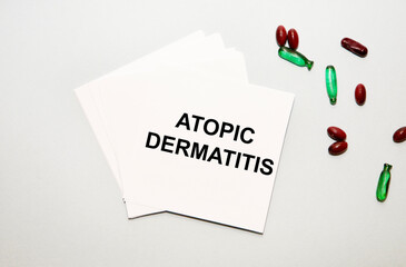 On the sheet for notes the text ATOPIC DERMATITIS, next to red and green capsules.