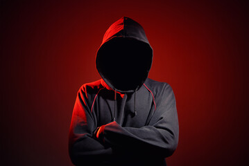 Silhouette af man without face in hood on red background. Anonymous crime concept