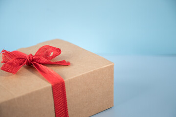 Gift with red ribbon on sky blue background.