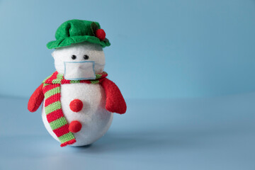 Snowman with mask on blue background. Christmas 2020.