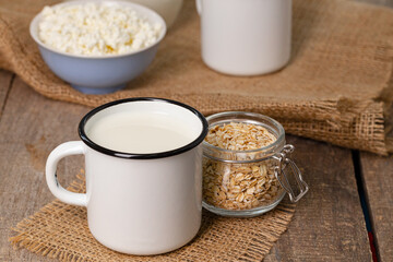 Glass of milk and oat flakes on wooden table