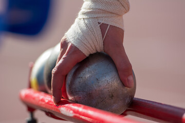 The athlete holds the projectile (shot) in the shot put. Close-up