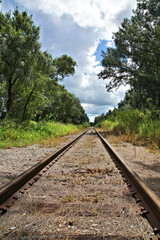 Fototapeta premium Railroad tracks through the countryside with clouds