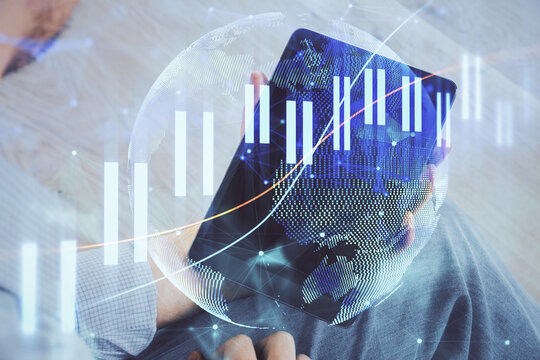 Double exposure of man's hands holding and using a digital device and forex graph drawing. Financial market concept.