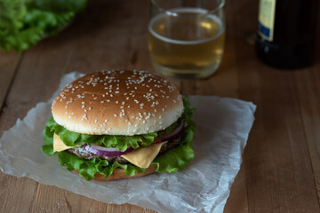 Burger with beer on a wooden table on a dark background