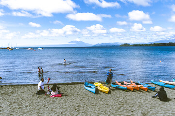 Large beautiful blue lake with boats and the Osorno volcano blurred in the background.