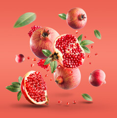 Flying in air fresh ripe whole and cut pomegranate with seeds and leaves isolated on red background.