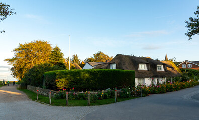 Obraz premium Amrum, Germany - October 16, 2020: Traditional thatched house and church in the morning