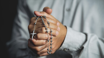christianity background of man hand holding rosary praying for god blessing