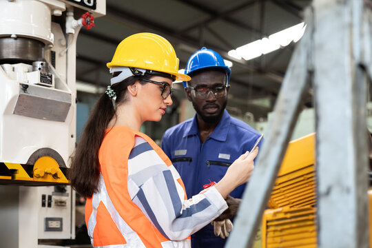 African American Male And Female Industrial Engineering In Safety Uniform, Hard Hats Working And Discussing In The Heavy Industry Manufacturing Factory