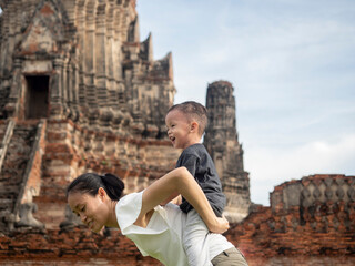 A son riding on the back of his mother playing in the park