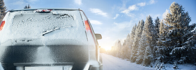 Car on a winter road through a snow covered forest.