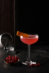 Alcoholic cocktails. Cosmopolitan. Drink from vodka, liqueur, mors and juice in a transparent glass on a black table, fresh cranberries. Bar menu. Background image, copy space, vertical © Nadia