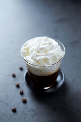 Coffee with whipped cream on dark stone background. Close up.