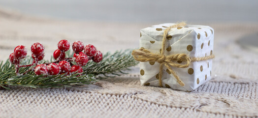 Cute gift box wrapped in dotted craft paper, tied with jute with a bow, on a knitted fabric , blured, tilt shift