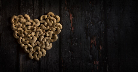heart shape cashew nuts on dark wooden table